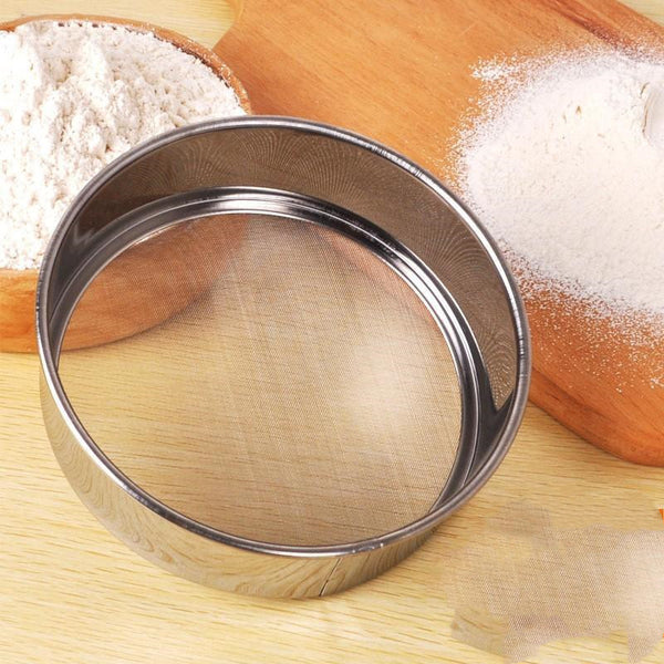 SteelSifter stainless steel flour sifter with ergonomic handle | Flour sifter with fine mesh screen for smooth baking | Stainless steel kitchen utensil sifting powdered sugar | SteelSifter sifting flour into mixing bowl | Durable stainless steel flour filter on wooden countertop | Ergonomic flour sifter used in baking preparation

